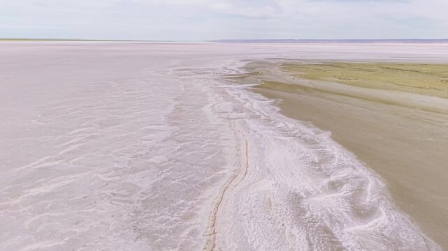 Aerial tracking shot over vast salt flats and dry shoreline