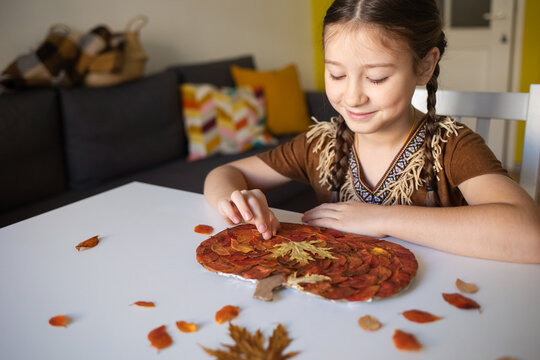 craft for kids. DIY autumn craft from leaves - pumpkin for thanksgiving day. create art for children. girl at home at the table.
