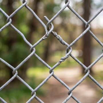 Chain link fence with twisted joint in a blurred outdoor setting  