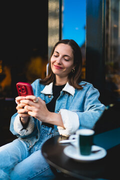 Serene Caucasian female student holding smartphone at cafe table with eyes closed, checking mobile banking budget goals tracking online payments and practicing mindful digital living