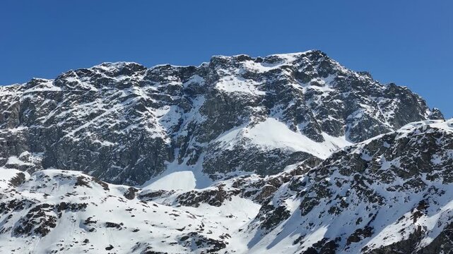 rugged mountain wall rises sheer above snowfields dark rock ribs streaked snow julier pass towering summit exposed cliffs graubunden switzerland high altitude alpine peak scenery