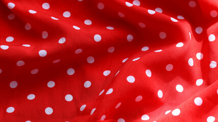 Red polka dot fabric texture background with soft folds. © Nelia