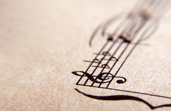 An old sheet of music with a treble clef, notes, and flats. Close-up. Copy space