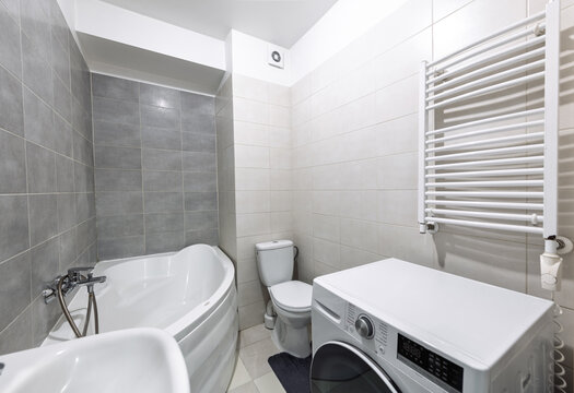 Modern Small Bathroom With Corner Bathtub, Washing Machine, Toilet and Heated Towel Radiator