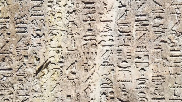 Ancient Egyptian hieroglyphic wall featuring densely carved horizontal rows of detailed stone inscriptions.