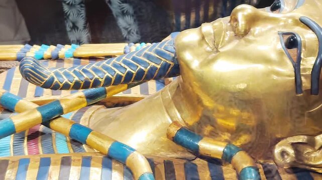 Tutankhamun's golden burial mask featuring blue inlays, a headdress, and arms crossed over the chest holding a crook and flail.