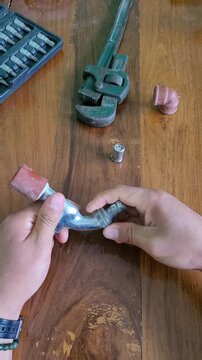 Hands Disassembling a Household Water Valve for Repair on Wooden Workbench