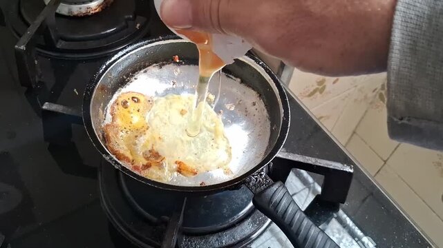 Raw egg cracking into hot frying pan