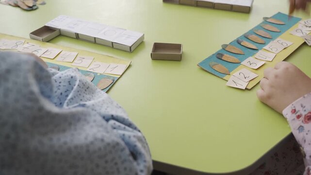 Engaged child learning through interactive play, arranging colorful number cards and wooden pieces on a vibrant green table, showcasing educational activities and cognitive development in a playful