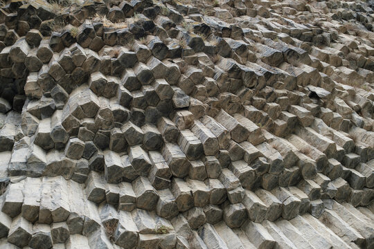 Geological formation features hexagonal basalt columns in Armenia, highlighting intricate stone patterns and textures on a rugged landscape