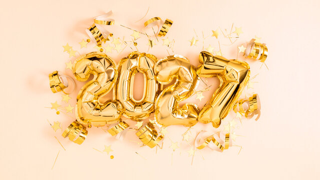 Happy New Year 2027 celebration background with golden foil balloons number 2027, confetti stars, and serpentine ribbons on pastel pink layout. Festive party, Christmas greeting card concept.
