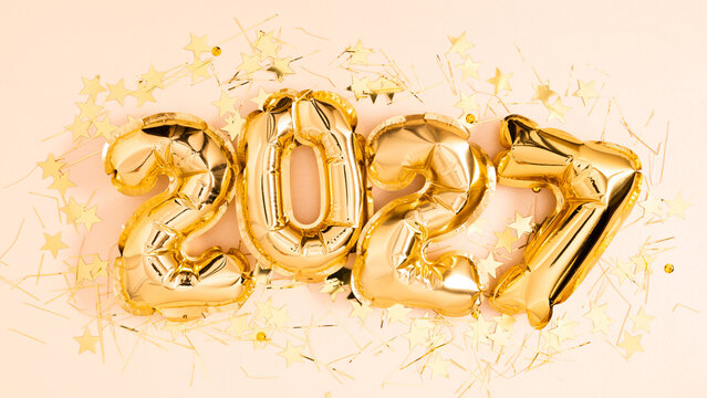 Happy New Year 2027 celebration background with golden foil balloon numbers 2027 aligned on pastel pink layout. Close up of festive party invitation, greeting card and winter holiday concept. 