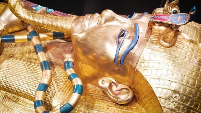Tutankhamun's golden burial mask featuring blue inlays, a headdress, and arms crossed over the chest holding a crook and flail.