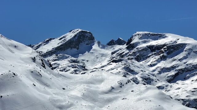 snowbound cirque rises toward twin rocky summits steep couloirs streak down slopes below julier pass alpine terrain graubunden switzerland high altitude european alps winter scenery