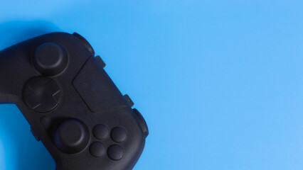 Close up flat lay of black wireless gamepad controller on blue background with copy space. Ideal for esports and gaming web banners.  © wibiwisnu