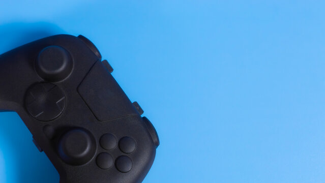 Close up flat lay of black wireless gamepad controller on blue background with copy space. Ideal for esports and gaming web banners.
