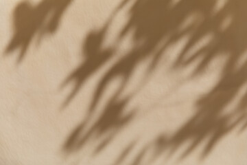 Obraz premium Blurred shadow of tree leaves fall across a light beige wall in bright sunlight. Minimalist botanical pattern, overlay effect, summer holiday relaxation, mediterranean vacation vibe.
