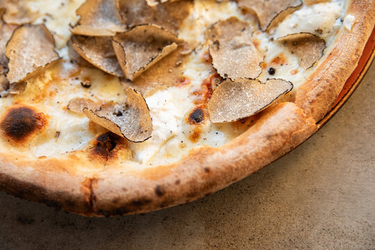 Close-up shot with selective focus and depth of field of wood fired pizza with fresh shaved truffles