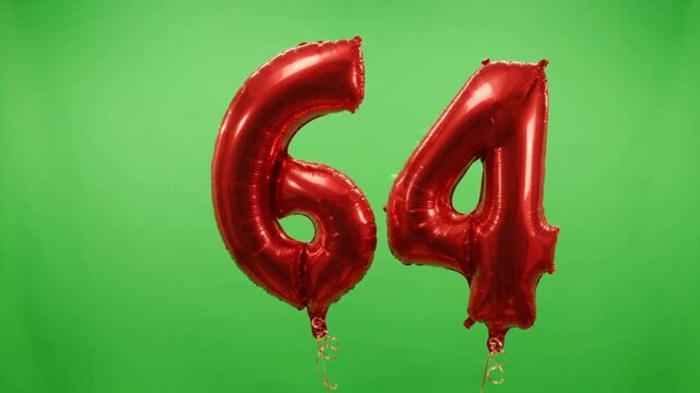 Red number 64 foil balloons on green screen, metallic sixty four birthday balloons, festive anniversary celebration decor on chroma key