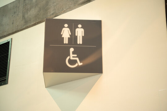 Modern restroom sign with gender neutral and wheelchair accessible icons on a white wall surface