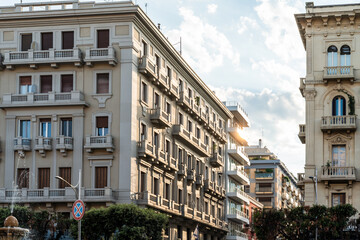 Row of historic Art Nouveau townhouses with ornate balconies and rows of windows in a southern European city at golden hour, wide shot of elegant facades in warm evening light with a cloudy sky, conc © daily_creativity