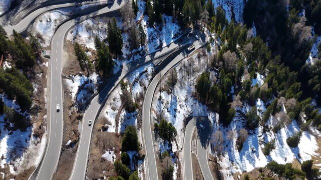 stacked hairpin loops birds eye view multiple cars coach wind switchback road malojaschlange mountain pass forested slope guardrails retaining walls graubunden switzerland