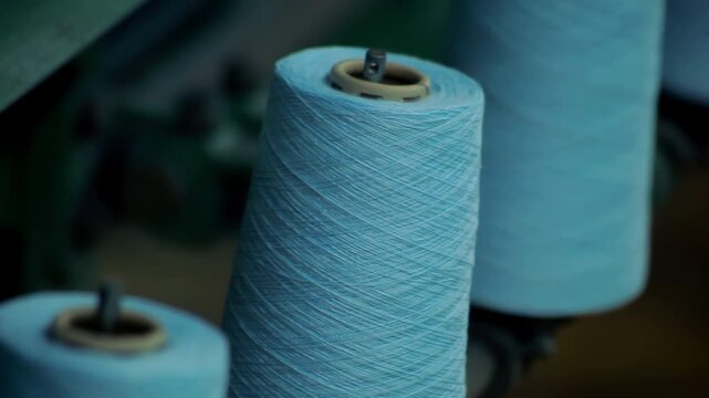 Cotton yarn cones rotating spinning machine. Close up thread bobbins factory.
