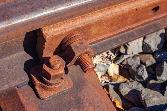 Macro view of heavy rusted steel bolts and nuts fastening railway track sleeper with copy space
