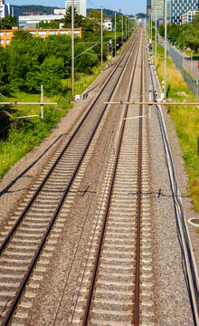Railway tracks leading into the distance with modern urban infrastructure and copy space