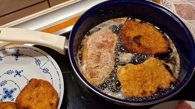 Close Up of Breaded Schnitzels Frying in Hot Oil Inside Pan