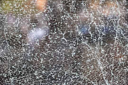 Abstract texture of fully shattered glass pane forming an intricate spiderweb network of cracks.
