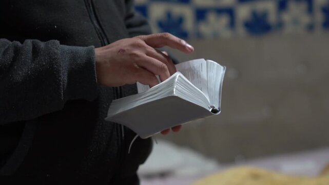 Man reading the Bible in a quiet indoor setting, spending time studying scripture and engaging in personal religious reflection.
