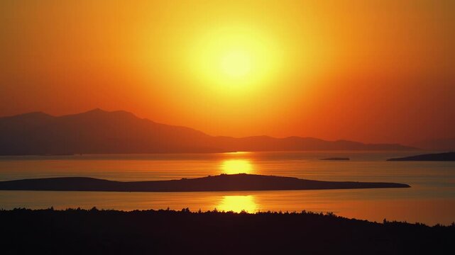 A vibrant golden sunset casts a warm glow over the Aegean Sea and its scattered islands, captured from the elevated viewpoint of Seytan Sofrasi (Devil's Feast) in Ayvalik, Turkey.