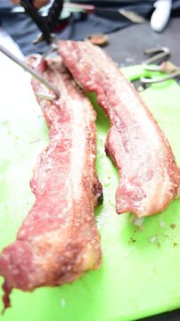 Close up of hands slicing freshly roasted crispy pork belly chicharron on a cutting board
