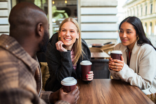 Three friends enjoying takeaway coffee at outdoor cafe