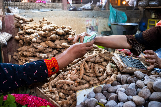 Customer paying cash for fresh spices at a traditional market stall.
