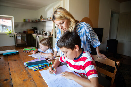 Mother helping children with homework at kitchen table