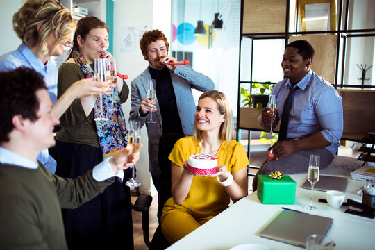 Coworkers celebrating birthday with cake in modern office