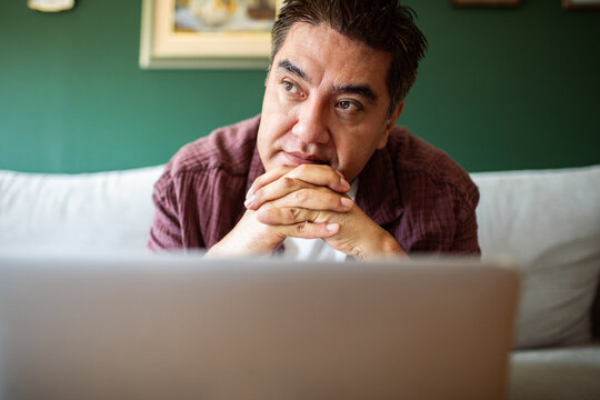 Pensive man thinking at laptop at home