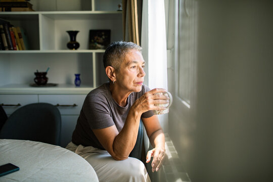 Senior woman drinking coffee by window at home