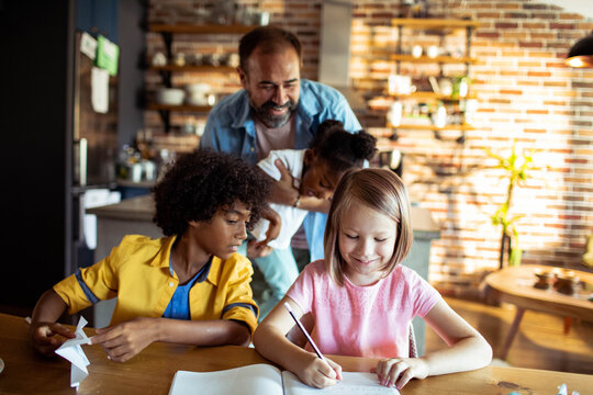 Caregiver helping children with homework at kitchen table