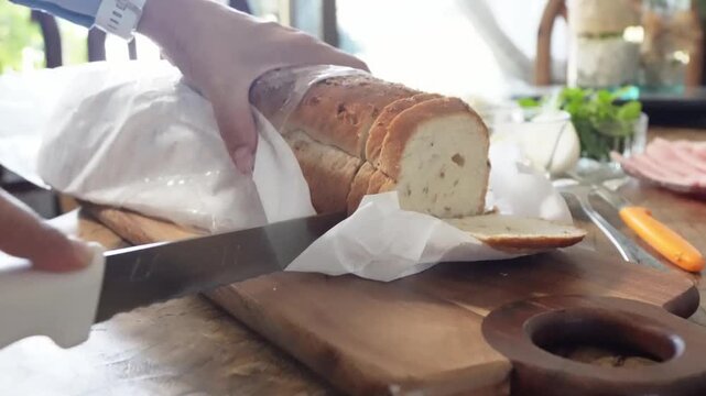 Hands Slicing Fresh Homemade Bread on Cutting Board