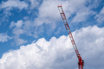 Large Construction Crane Against Blue Sky and White Clouds. Large Crane Silhouette Against Blue Sky and Clouds. Massive Construction Crane at a High Rise Building Site. © onderortel