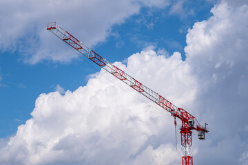 Large Construction Crane Against Blue Sky and White Clouds. Large Crane Silhouette Against Blue Sky and Clouds. Massive Construction Crane at a High Rise Building Site. © onderortel