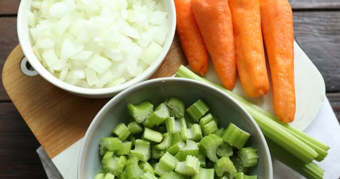 Cut carrots, onions and celery on wooden table, spinning. Top view