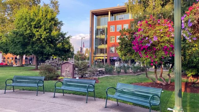 Green park benches in front of Puyallup City Hall with colorful hanging flower baskets - Puyallup WA, USA - September 12, 2026