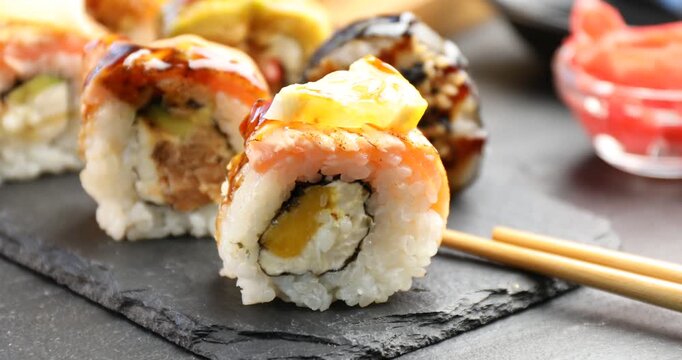 Tasty sushi rolls and soy sauce on black table, closeup
