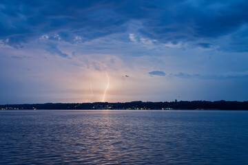 Lightning striking over calm water with cloudy blue sky at dusk in flensburg © Holger