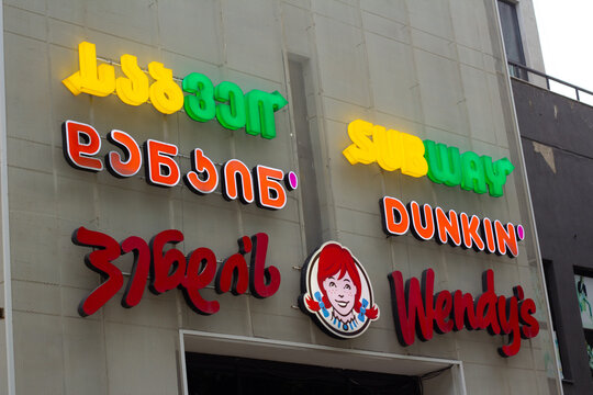 Tbilisi, Georgia - June 29, 2026: Horizontal street photo. Bottom view. Logo of fastfood cafe Subway, Dunkin Donuts, Wendy's on mall wall. Fast food menu, dinner, lunch, pick up order, diet, eat
