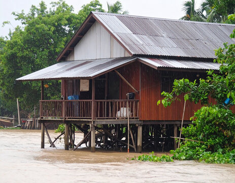 Stilt House Surrounded by Rising Flood Waters in Rural Landscape During Severe Weather Disaster And Environmental Emergency